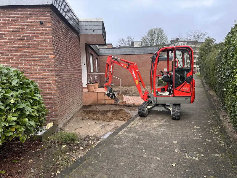 Minibagger beim Aushub vor einem Klinkerhaus