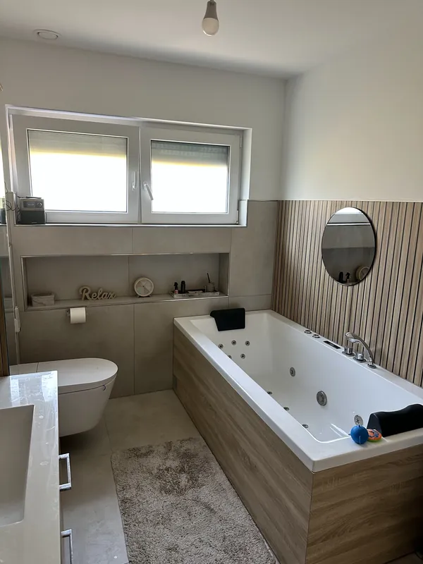 Neues Bad mit Whirlpool-Wanne und Holzwaschtisch nach der Sanierung in Kaarst